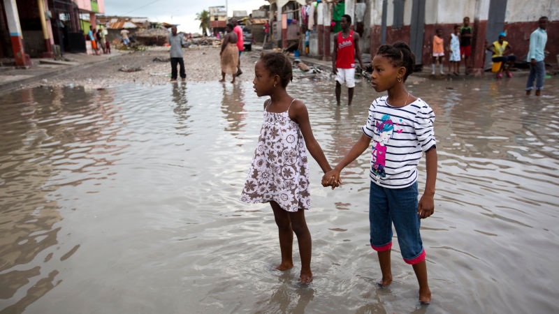 Dos niñas se toman de la mano y se ayudan a pasar por una calle inundada debido a Matthew por Les Cayes, Haití. La foto fue tomada el 6 de octubre, dos días después del paso del huracán por la nación. (Foto: AP).